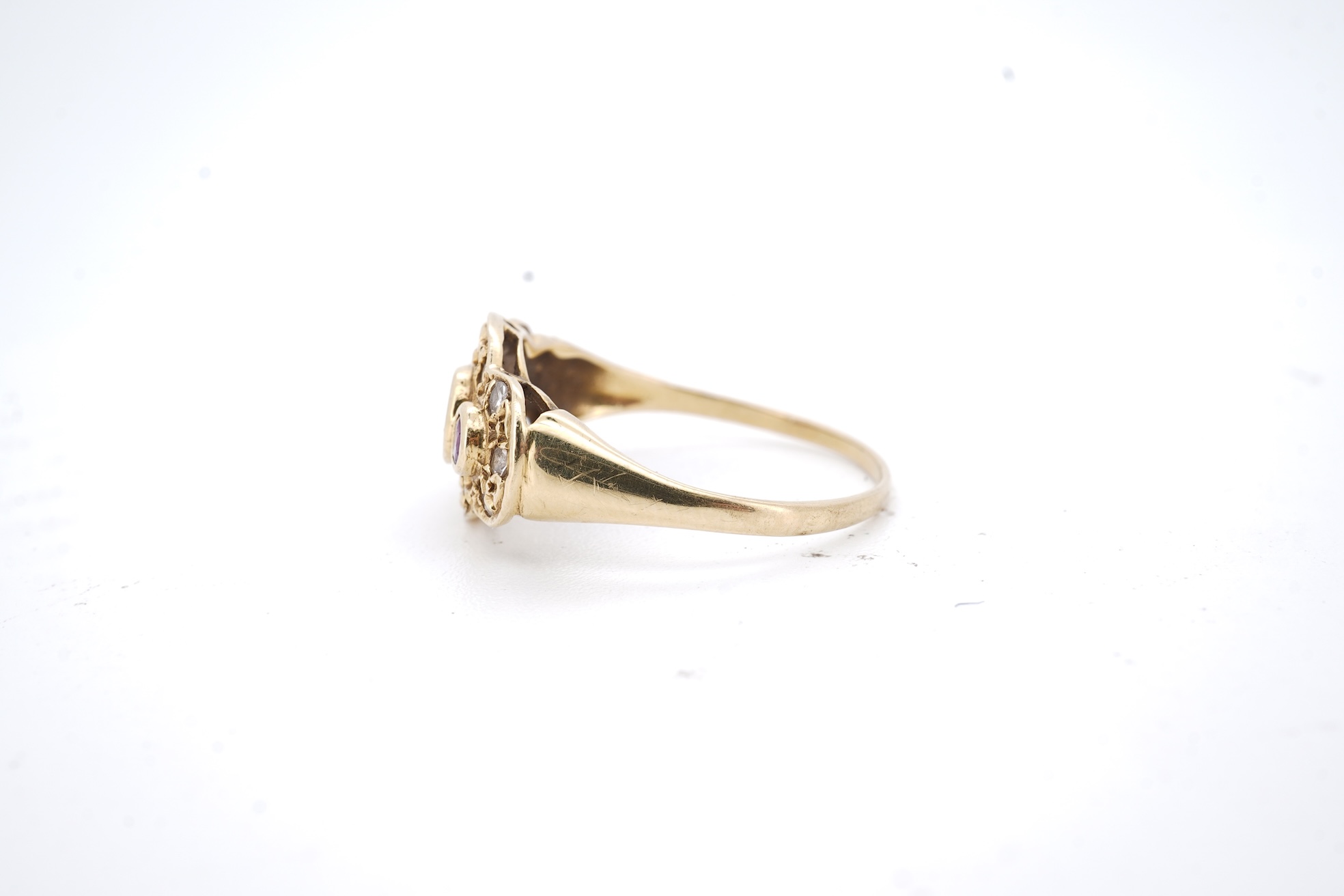 A modern 18ct gold, ruby and diamond cluster ring, the three rubies bordered by small round brilliants, size O, gross weight 2.3 grams.